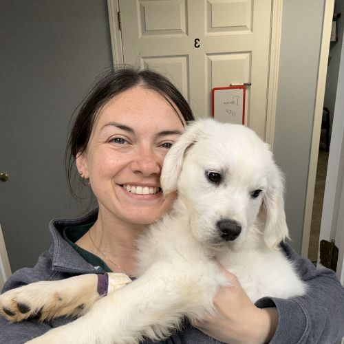 A woman cradles a small white puppy in her arms