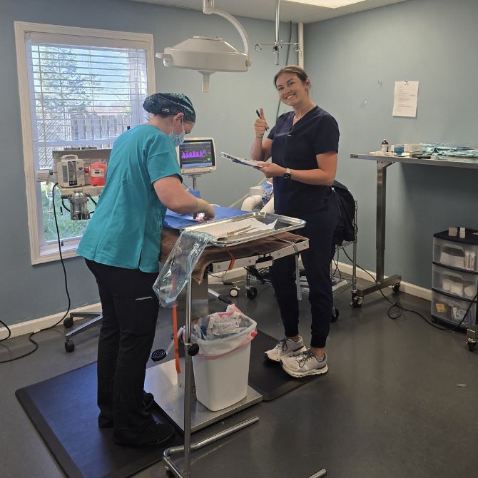 Two women stand in a room with a medical table